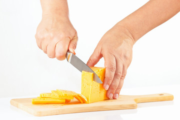 Female hands sliced cheese on a cutting board close up