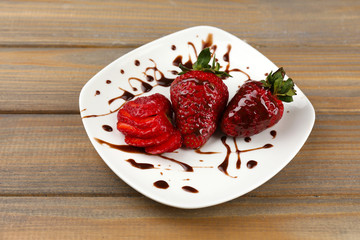 Red ripe strawberries with chocolate on wooden table
