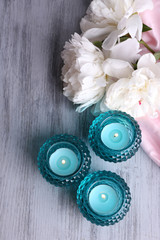 Glass candlesticks and flowers on color wooden background
