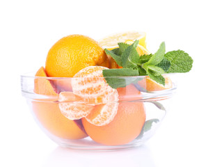 Fresh citrus fruits with green leaves in glass bowl, isolated