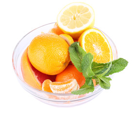 Fresh citrus fruits with green leaves in glass bowl, isolated