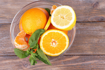 Fresh citrus fruits with green leaves in glass bowl