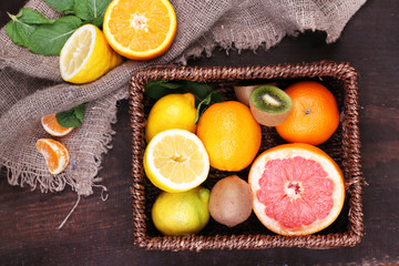 Obraz na płótnie Canvas Fresh exotic fruits with green leaves in wicker basket