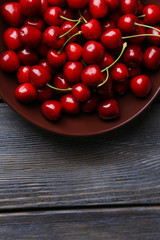 Sweet cherries  on plate on wooden background