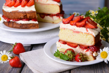 Delicious biscuit cake with strawberries on table close-up