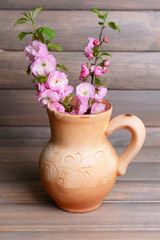 Beautiful fruit blossom in pitcher on table on grey background