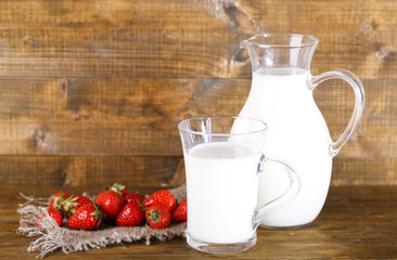 Ripe sweet strawberries in wooden bowl and jug with milk