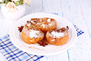 Baked pears with syrup on plate, on color wooden background
