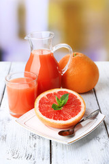 Half of grapefruit, glass jug with fresh juice and spoon