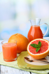 Half of grapefruit, glass jug with fresh juice and spoon