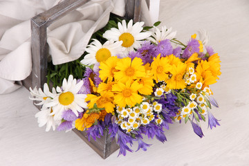 Beautiful flowers in crate on light background