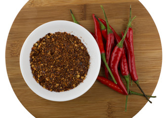 Red chili peppers and crushed chilli on wooden plate