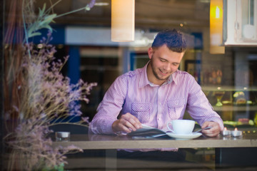 Portrait of a young man reading and drinking coffee