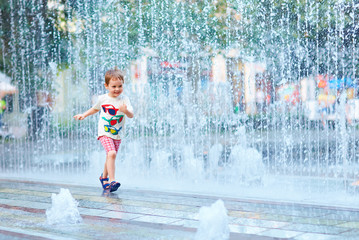 excited boy running between water flow in city park