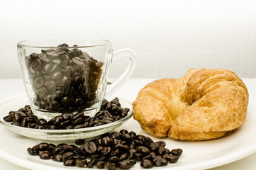 Cup of coffee beans with croissant