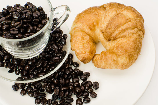 Cup of coffee beans with croissant