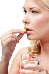 Blond woman with glass of water takes pills, isolated