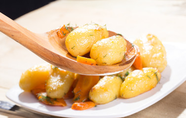 Roasted potatoes with carrot on the wooden ladle
