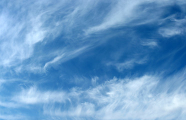 Blue sky background with wavy fleecy clouds
