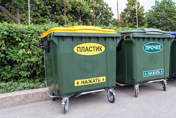 Green dumpsters on a city street with inscription on russian