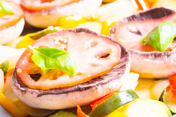 Raw mushrooms with cooked vegetables and leafs of basil