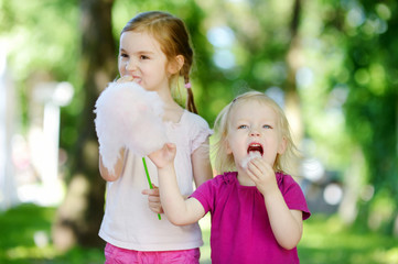 Obraz premium Adorable little sisters eating candy-floss