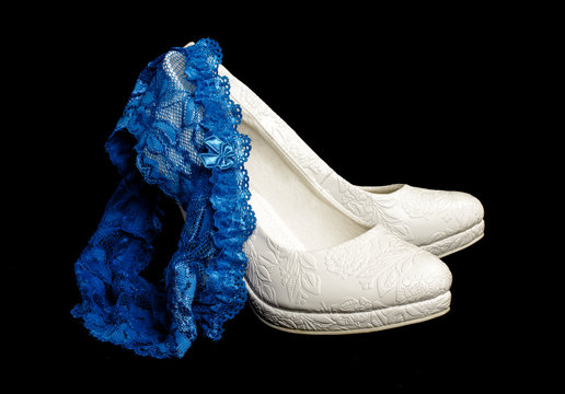 Blue wedding garter on the pair of bridal shoes