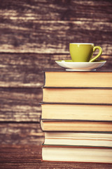 Books and cup of coffee on wooden background.