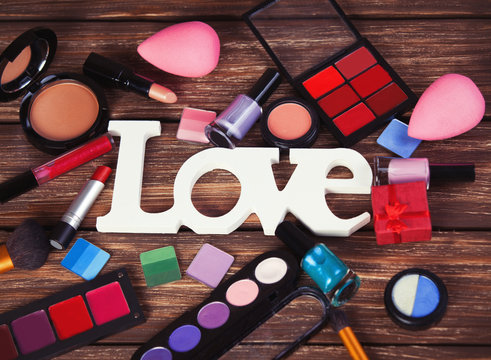 Cosmetics and word Love on wooden table