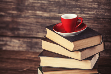 Books and cup of coffee on wooden background.