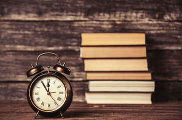 Alarm clock and books on wooden table.
