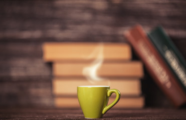 Books and cup of coffee on wooden background.