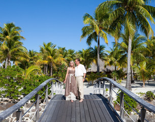 Loving couple on wooden bridge on the tropical island - obrazy, fototapety, plakaty