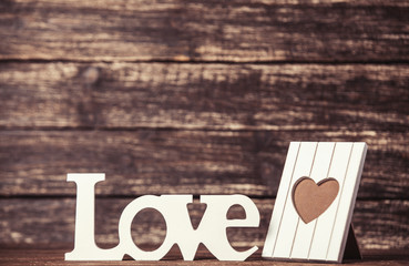 Word Love and frame for photo on wooden table.