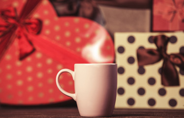 Cup of coffee and gifts on background.
