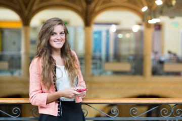 Portrait of a beautiful girl using a mobile phone in university © peppinuzzo