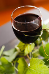 Red wine in glass with grape leaves