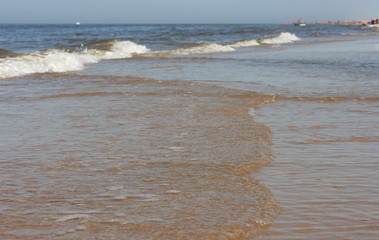Waves with white crests inundate the sandy beach