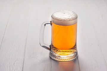 Mug of beer on wooden background