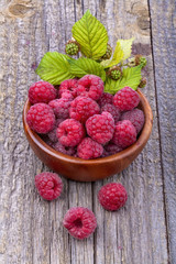 Healthy organic raspberries in a bowl on the old rustic table