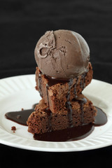 Slices of  brownie covered with chocolate and chocolate ice crea