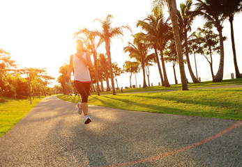 young asian woman running at sunrise tropical park 