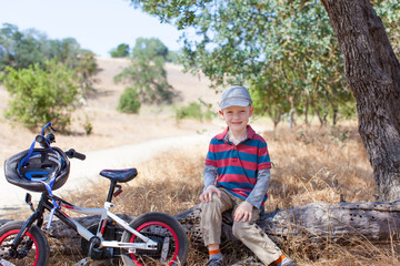 handsome little boy resting in the park after riding the bicycle