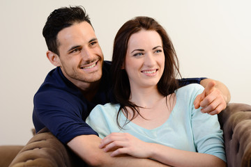 Obraz premium happy lovely young couple at home in sofa watching tv together