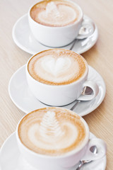 Three white cups of assorted coffee on table