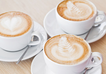 Three white cups of assorted coffee on table