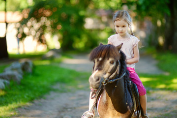 Adorable little girl riding a pony