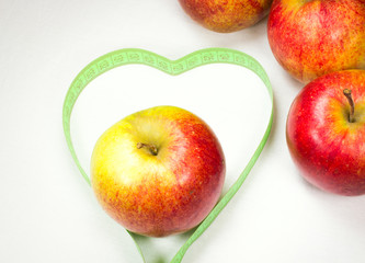 red apples with measuring tape forming a heart shape