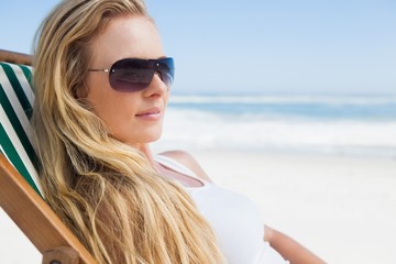 Gorgeous blonde in sunglasses sitting at the beach