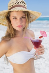 Pretty blonde holding cocktail on the beach